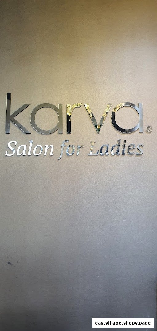 Close-up of the elegant 'KARVA Salon for Ladies' sign on a wall.