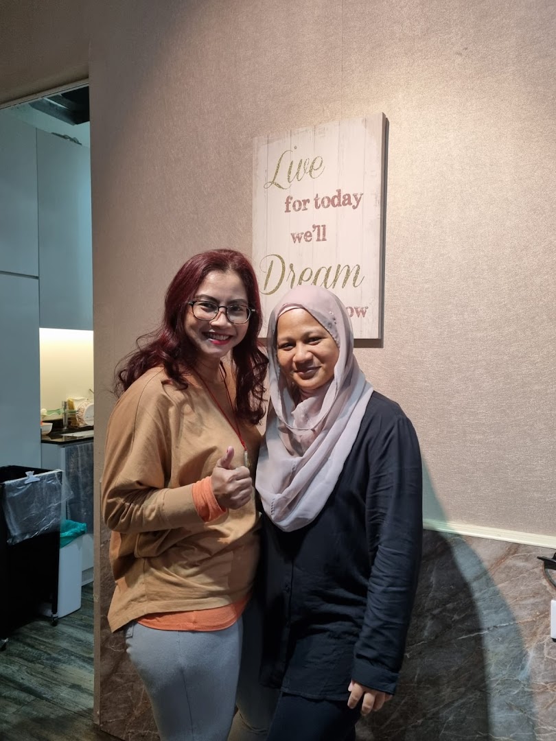 Two smiling women, one giving a thumbs up, inside KARVA Salon for Ladies with a motivational sign.