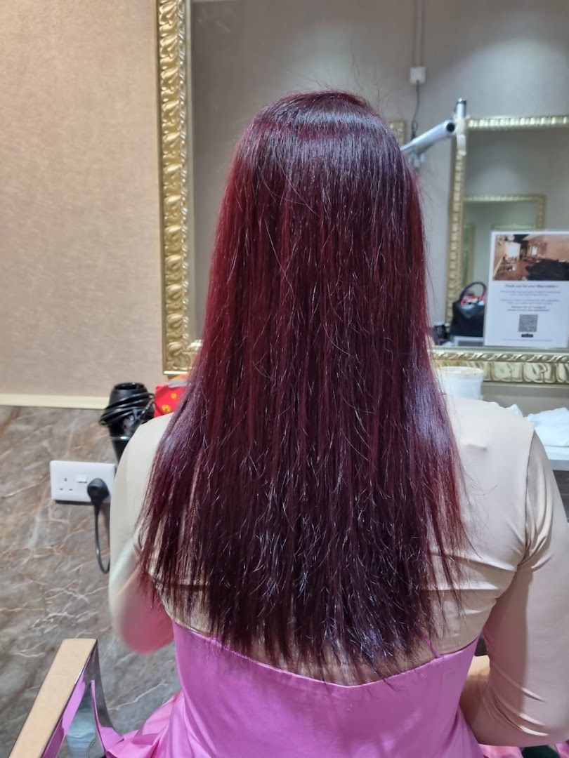 A client's long, dark red hair after a salon treatment, viewed from behind in a salon setting.
