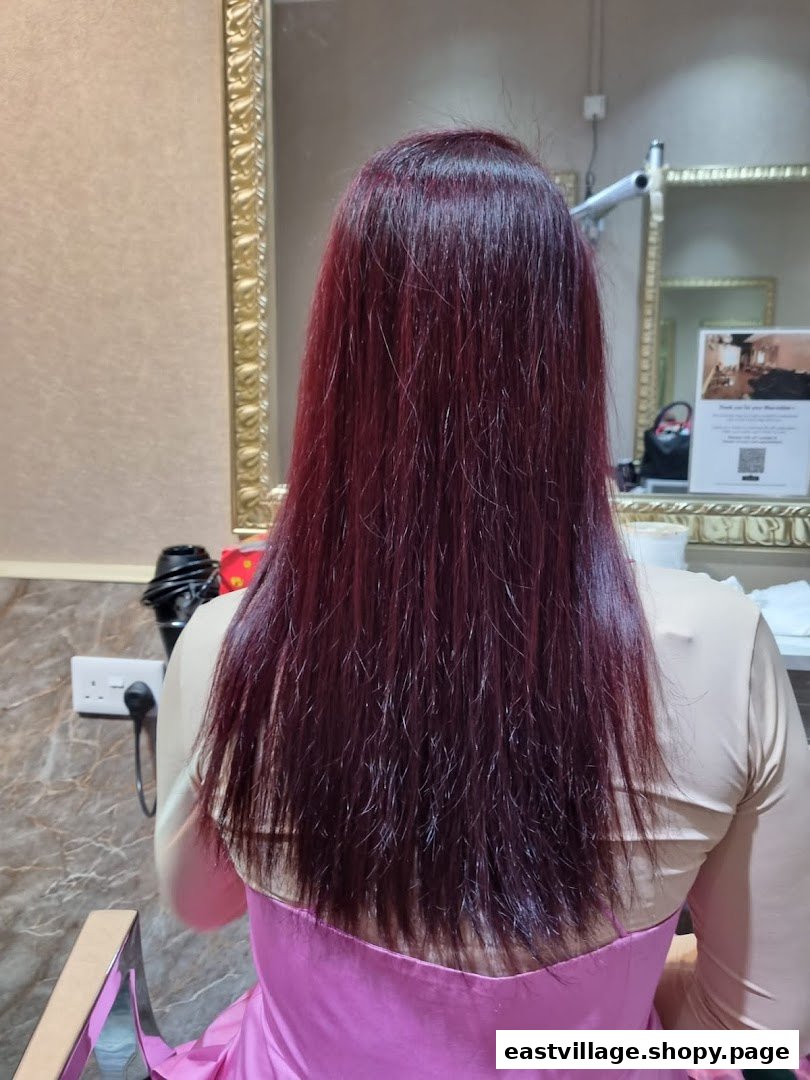 A client's long, dark red hair after a salon treatment, viewed from behind in a salon setting.