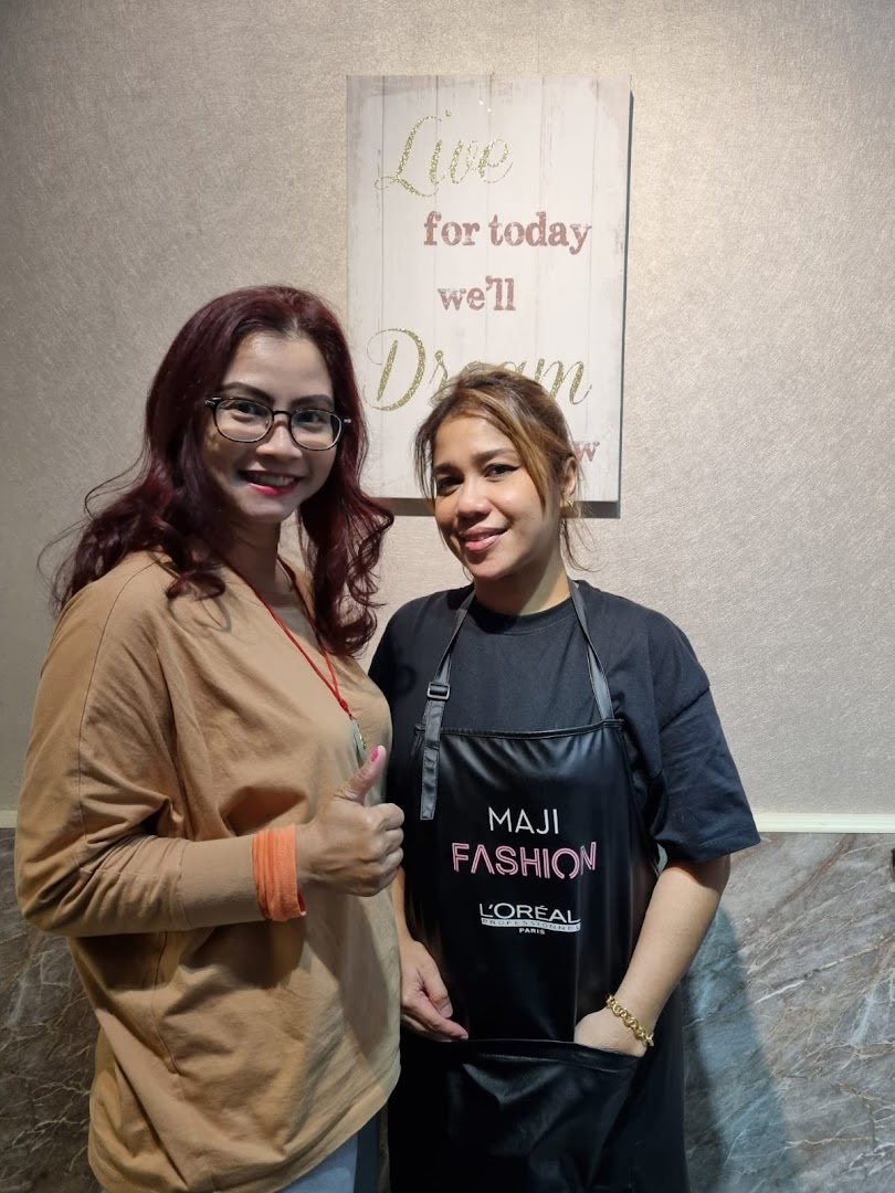 Two smiling women, one in a L'Oréal apron, inside KARVA Salon.