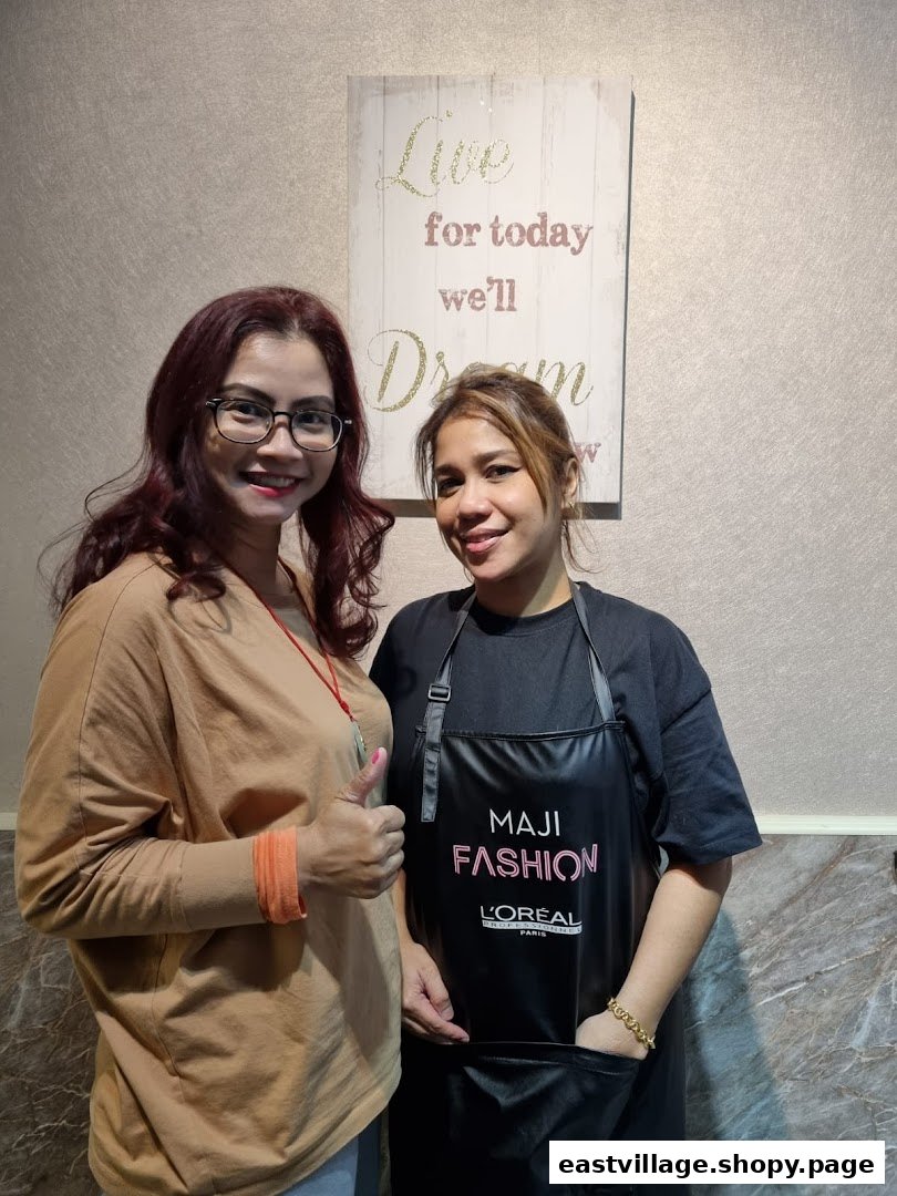Two smiling women, one in a L'Oréal apron, inside KARVA Salon.