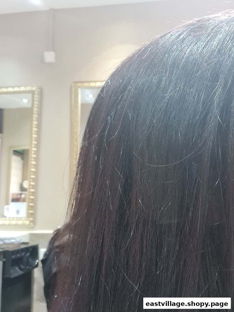 Close-up of a client's dark hair inside a salon, with ornate mirrors in the background.