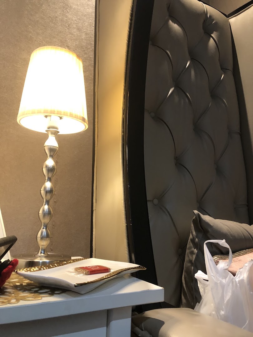 An elegant interior shot featuring a lamp, side table with a small item, and a luxurious tufted chair.