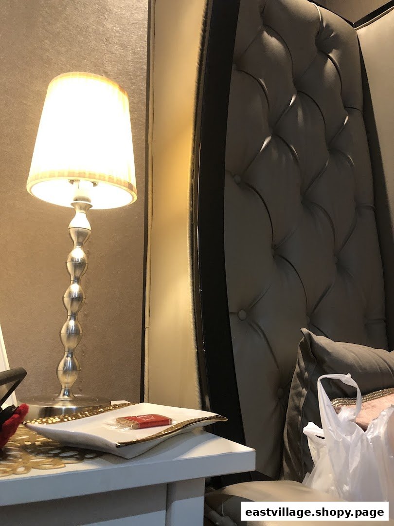 An elegant interior shot featuring a lamp, side table with a small item, and a luxurious tufted chair.