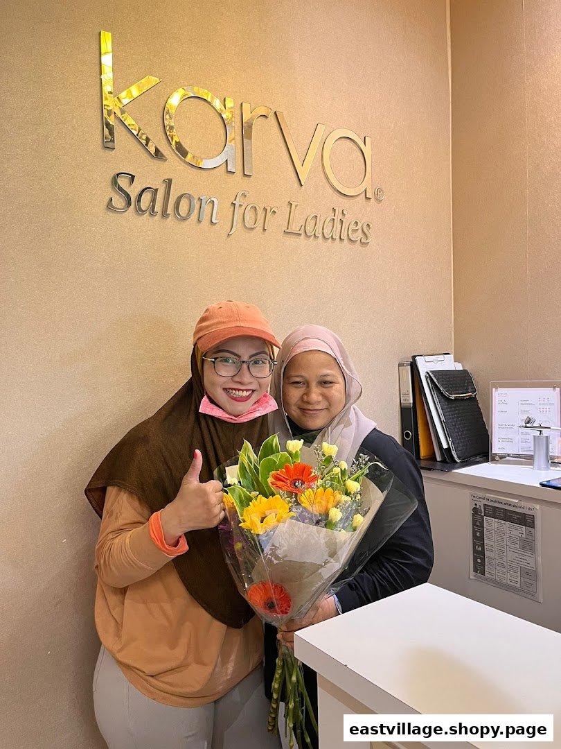 Two smiling women with flowers inside KARVA Salon for Ladies, featuring the shop's logo.