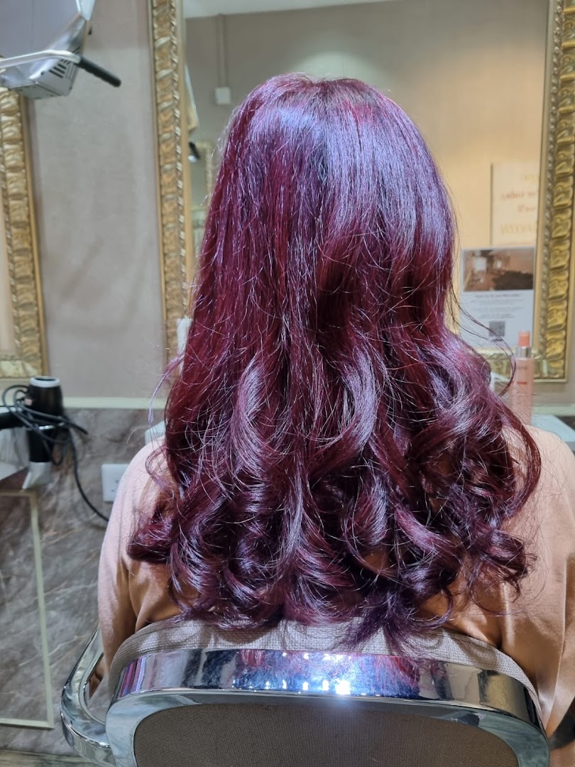 A person with vibrant purple-red hair, freshly styled, sitting in a salon chair.