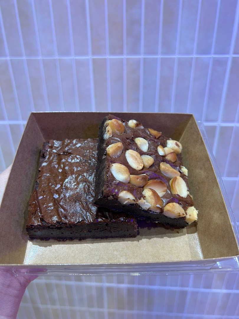 Two delicious brownies, one with sea salt and one with macadamia nuts, presented in a takeaway box.