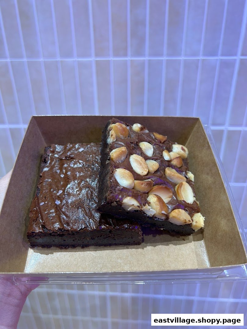 Two delicious brownies, one with sea salt and one with macadamia nuts, presented in a takeaway box.