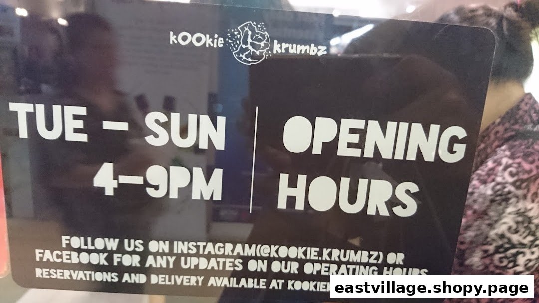 A sign displaying KookieKrumbz's opening hours (Tue-Sun, 4-9 PM) and social media contact information.