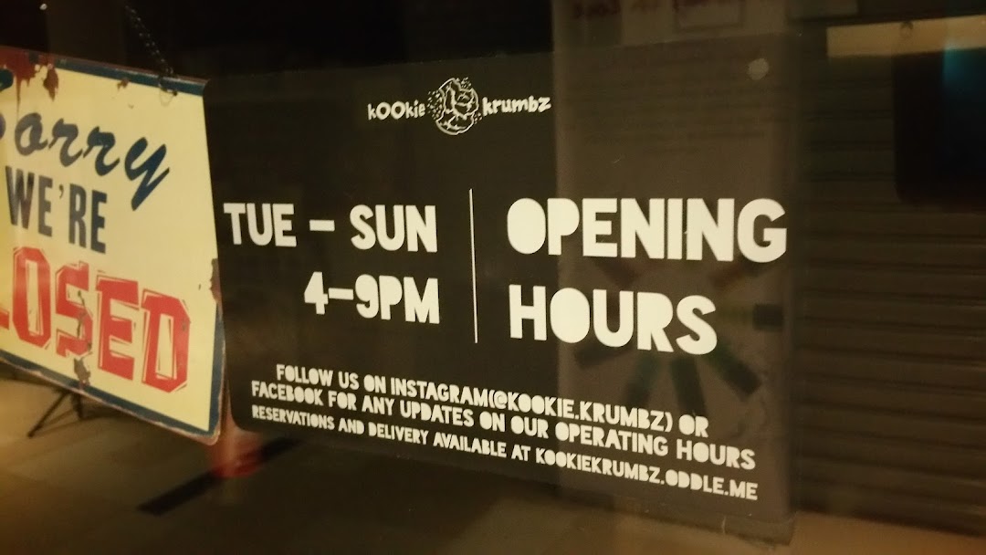 KookieKrumbz shop front displaying opening hours and contact information.
