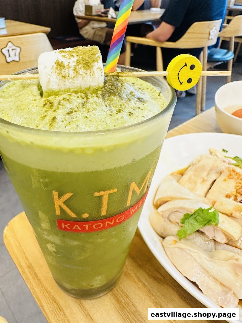 A vibrant green tea drink with marshmallow and a plate of chicken rice at KTMW Katong Mei Wei.