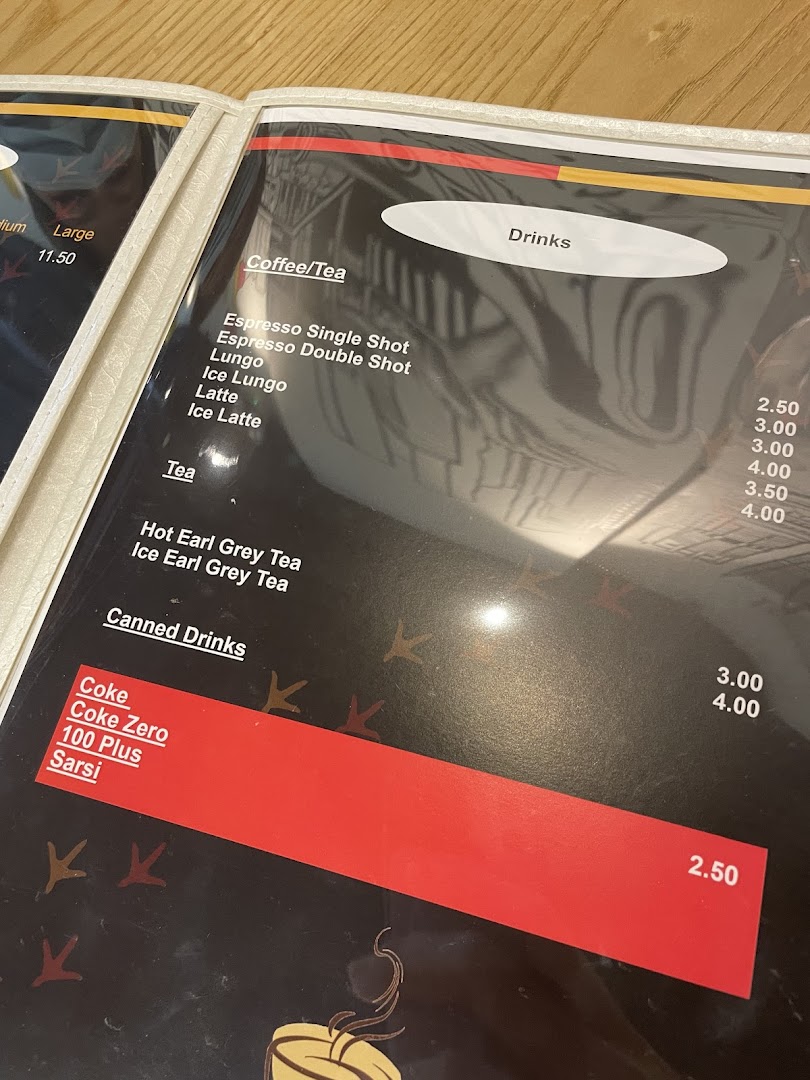 A close-up view of the drinks section of a cafe's menu, featuring coffee, tea, and canned beverages.