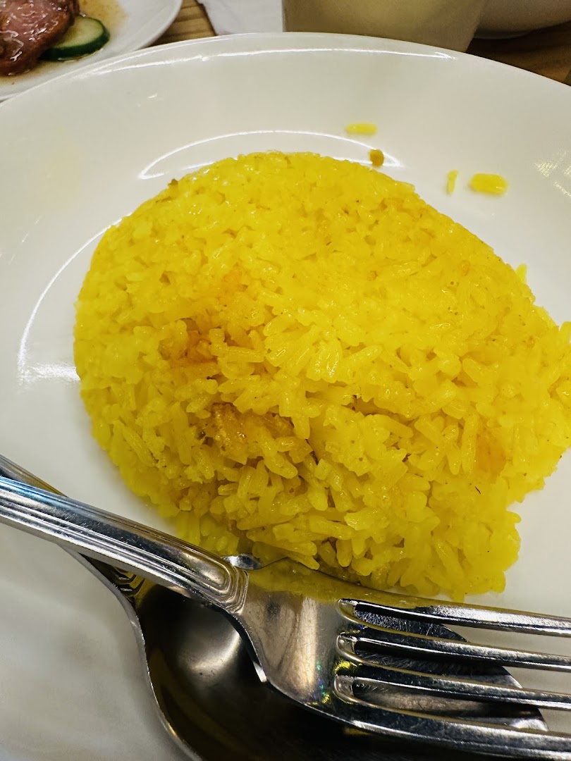 A close-up of a plate of vibrant yellow rice with a fork and spoon.