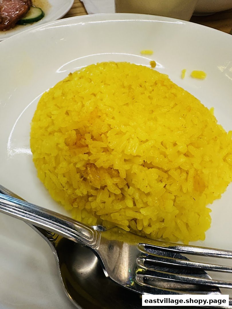 A close-up of a plate of vibrant yellow rice with a fork and spoon.