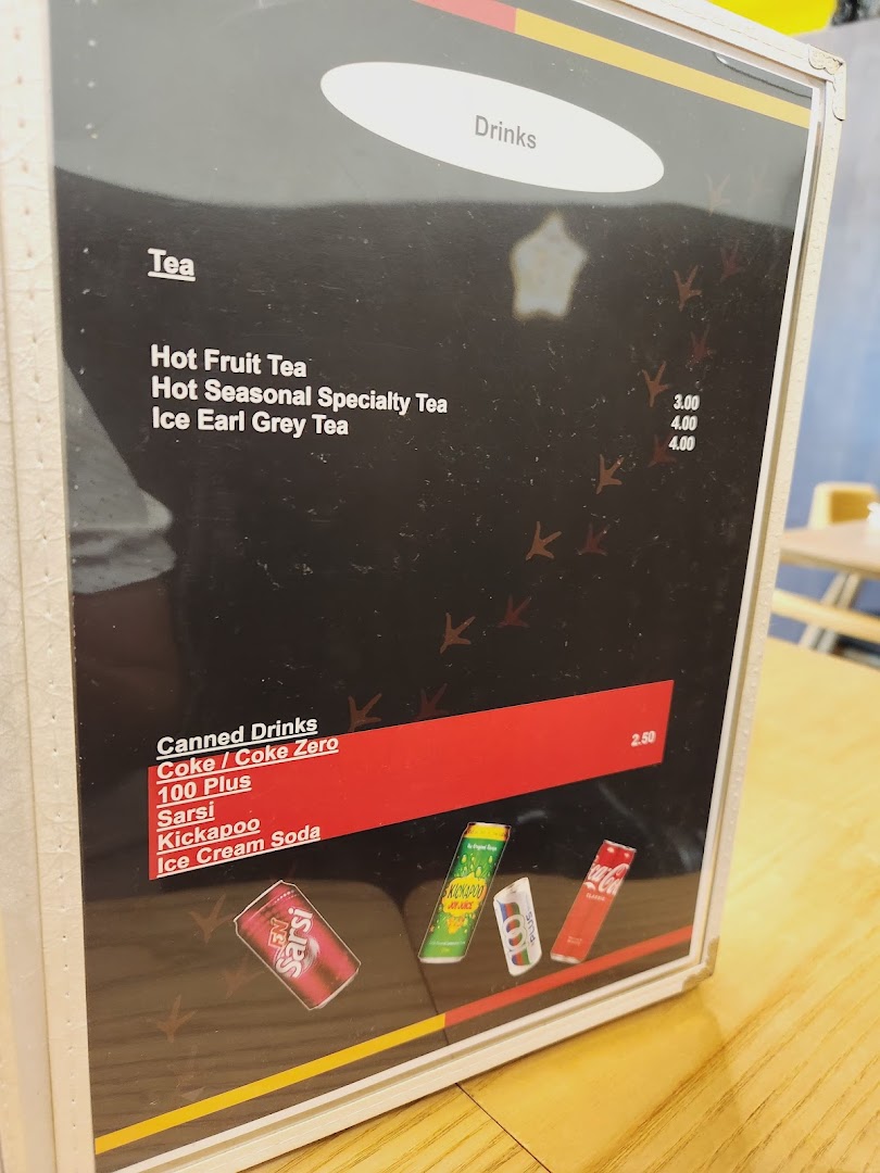 A close-up of a drinks menu board featuring teas and canned beverages with prices.