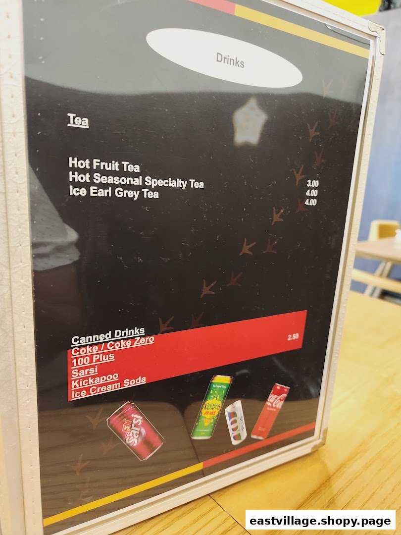A close-up of a drinks menu board featuring teas and canned beverages with prices.