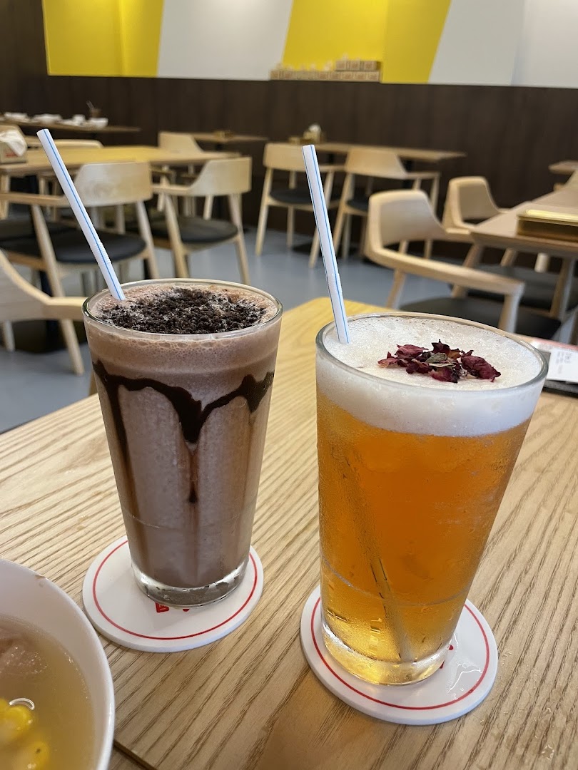 Two refreshing drinks, a chocolate shake and a tea, on a wooden table in a cafe.