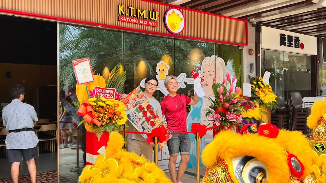 The shop front of KTMW Katong Mei Wei chicken rice tea-cafe, adorned with grand opening decorations and two individuals.