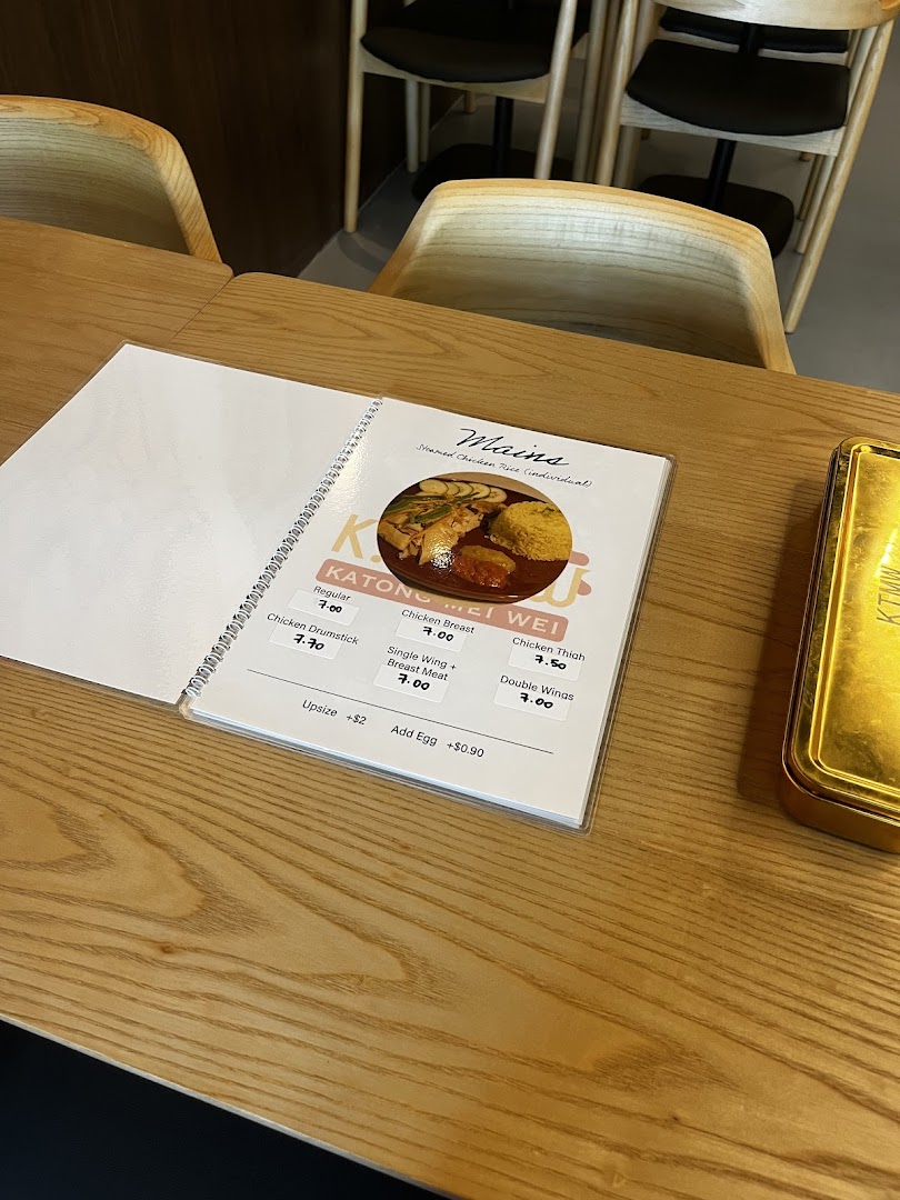 A menu displaying chicken rice options on a wooden table at KTMW Katong Mei Wei.
