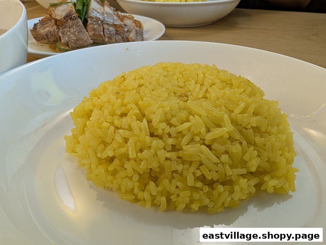 A close-up of fragrant yellow chicken rice served on a white plate.