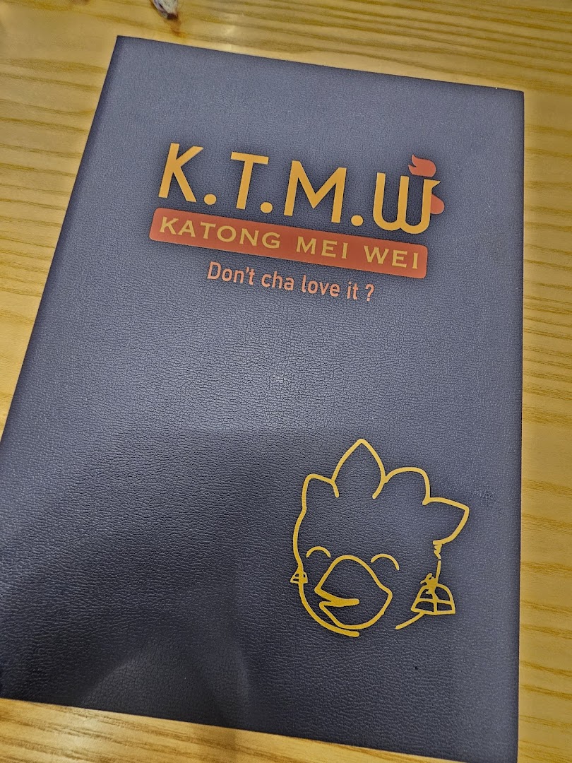 Close-up of a dark blue folder/menu cover featuring the KTMW Katong Mei Wei logo and slogan.