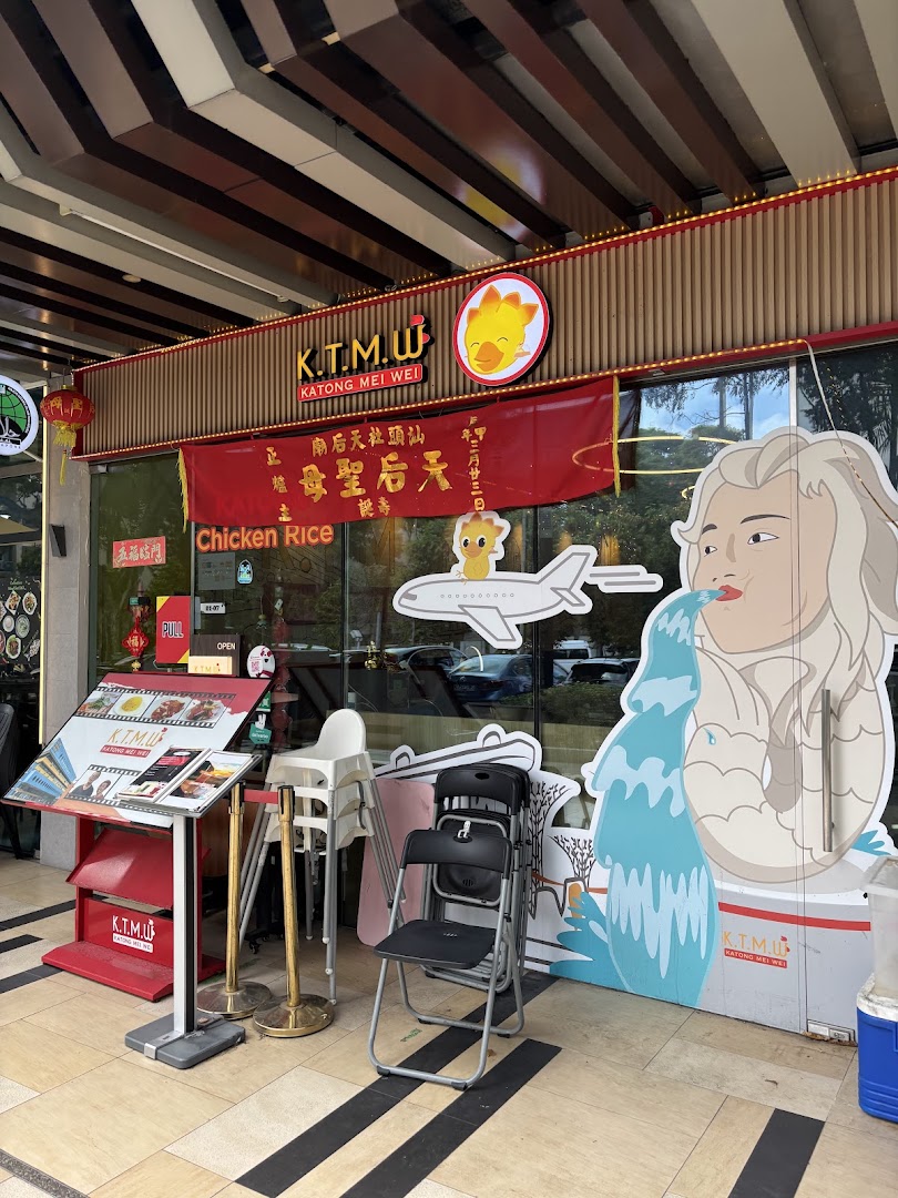Exterior view of KTMW Katong Mei Wei chicken rice cafe with prominent signage and a Merlion-like standee.