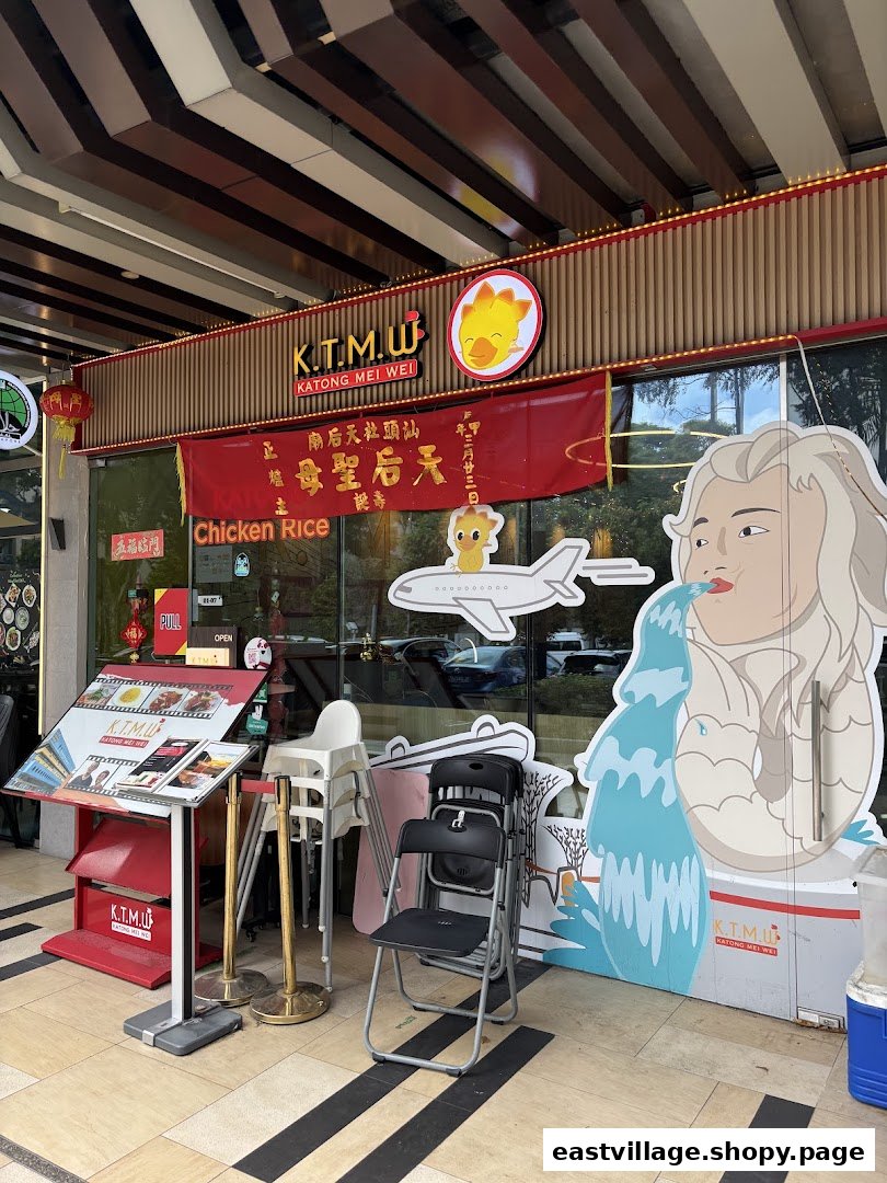 Exterior view of KTMW Katong Mei Wei chicken rice cafe with prominent signage and a Merlion-like standee.