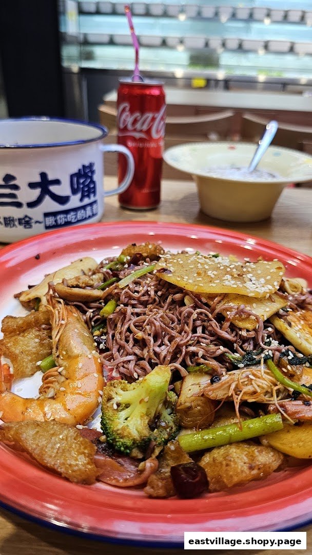 A vibrant plate of stir-fried noodles with shrimp, vegetables, and other ingredients, alongside a drink.