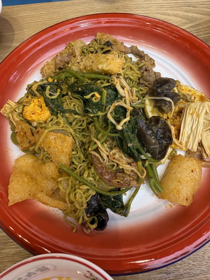 A vibrant plate of mixed noodles, vegetables, and various ingredients served on a classic red-rimmed dish.