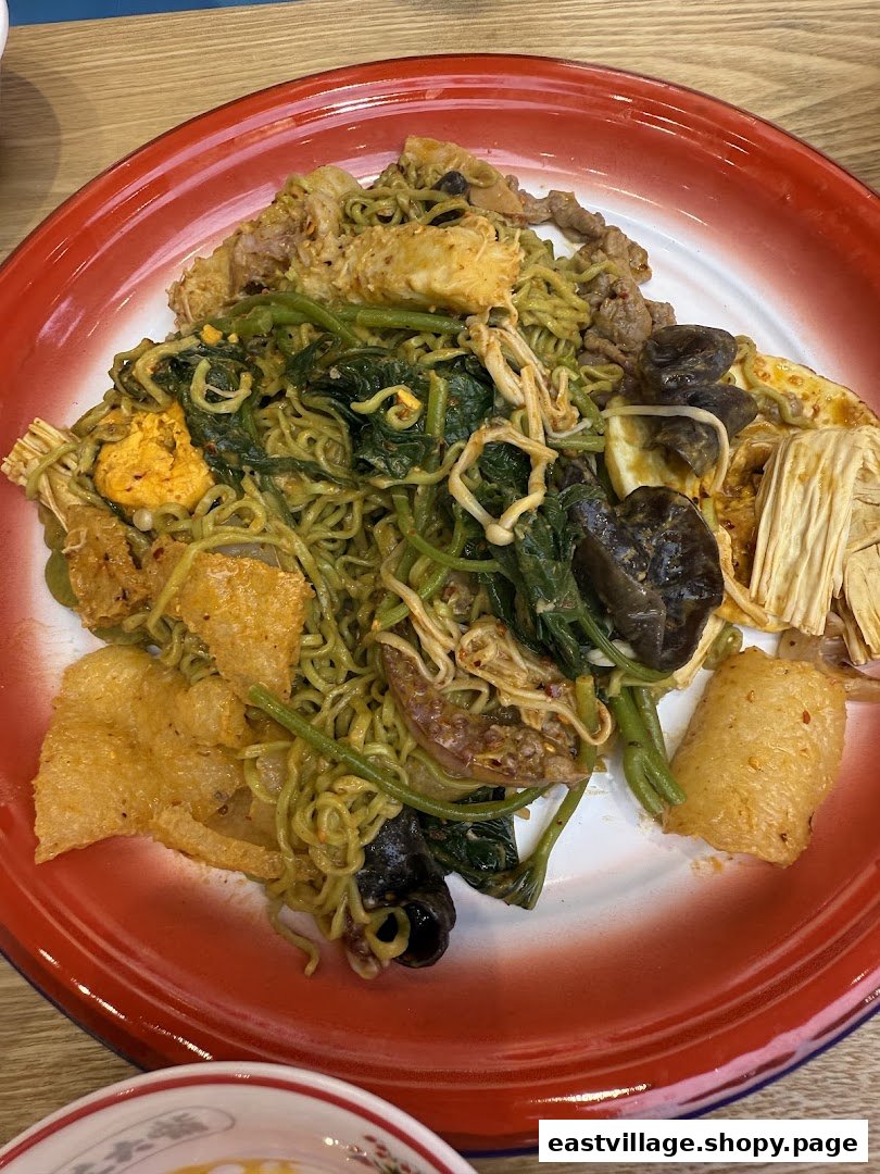 A vibrant plate of mixed noodles, vegetables, and various ingredients served on a classic red-rimmed dish.