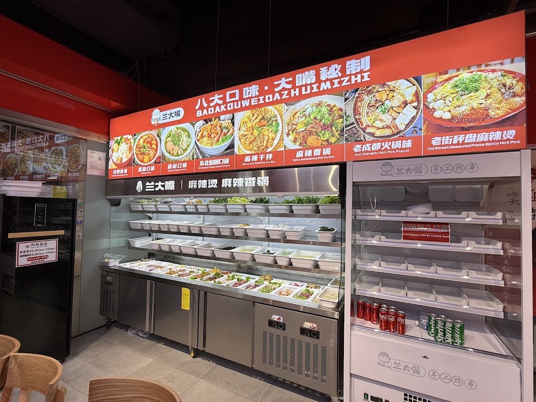 A vibrant self-serve hot pot and malatang station with a variety of fresh ingredients and a menu board.