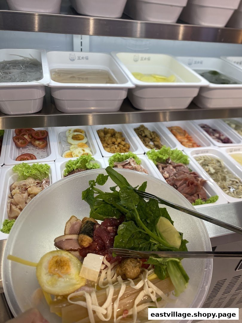 A customer's bowl filled with ingredients, with a self-service display of fresh hot pot items in the background.