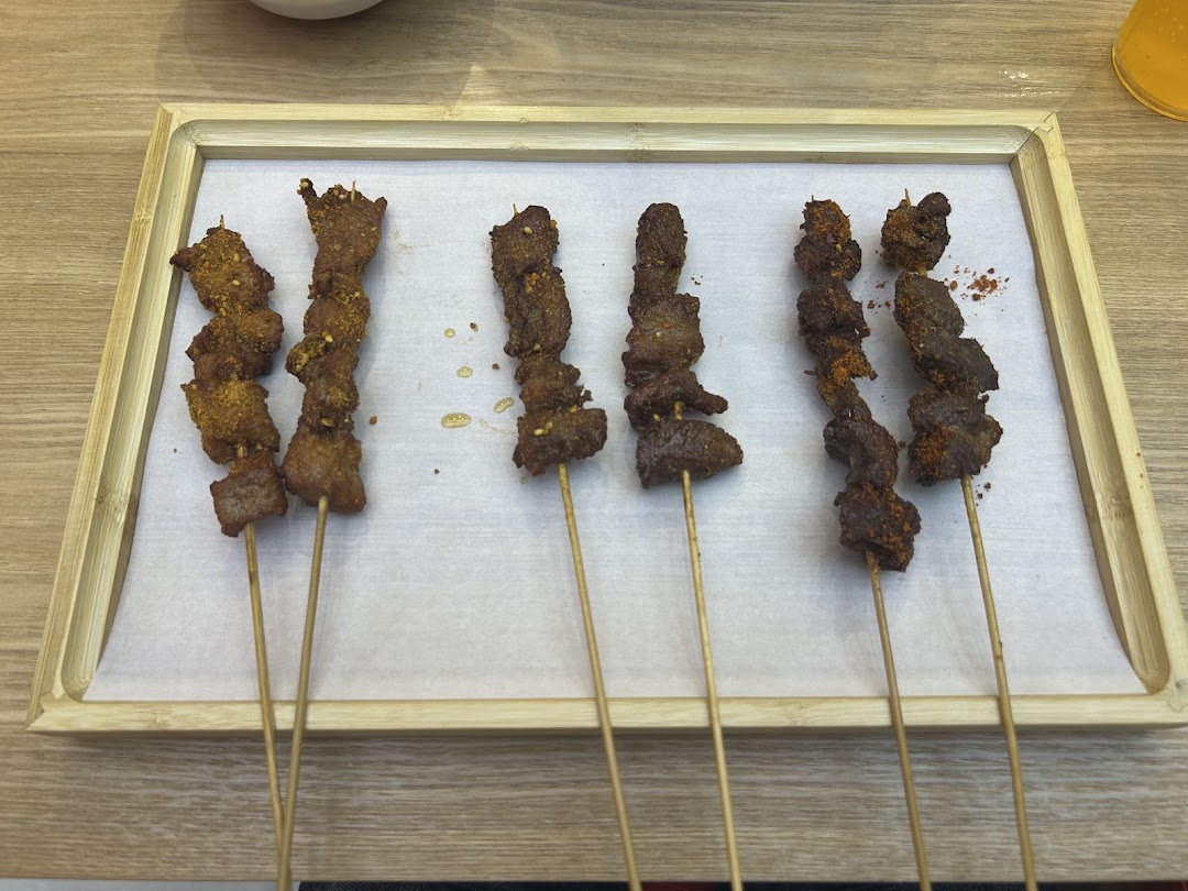 Six delicious skewers of seasoned meat served on a bamboo tray.