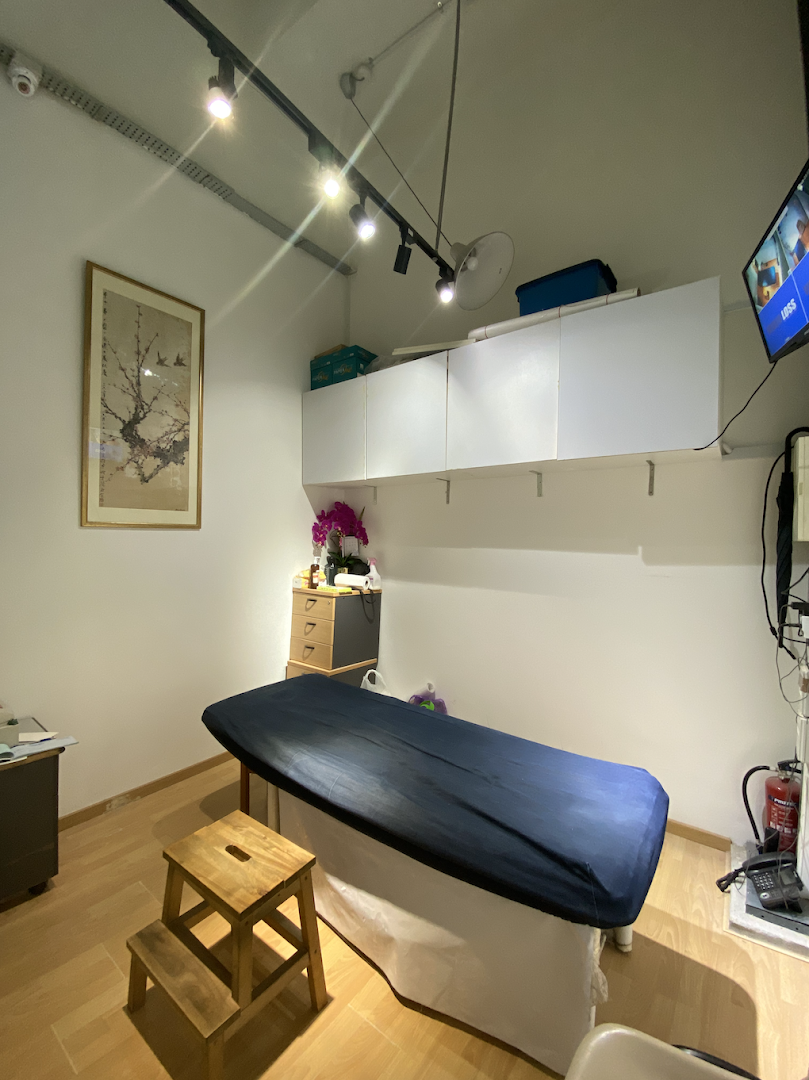 An interior view of a therapy room with a treatment bed and minimalist decor.