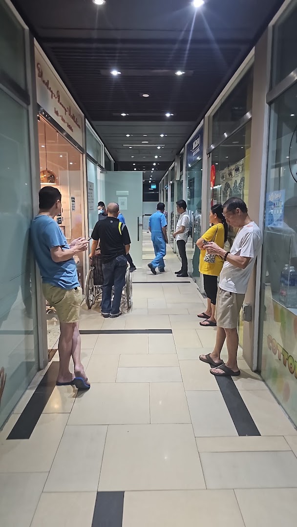 People waiting in a brightly lit mall corridor lined with various shop fronts, including a therapy center.