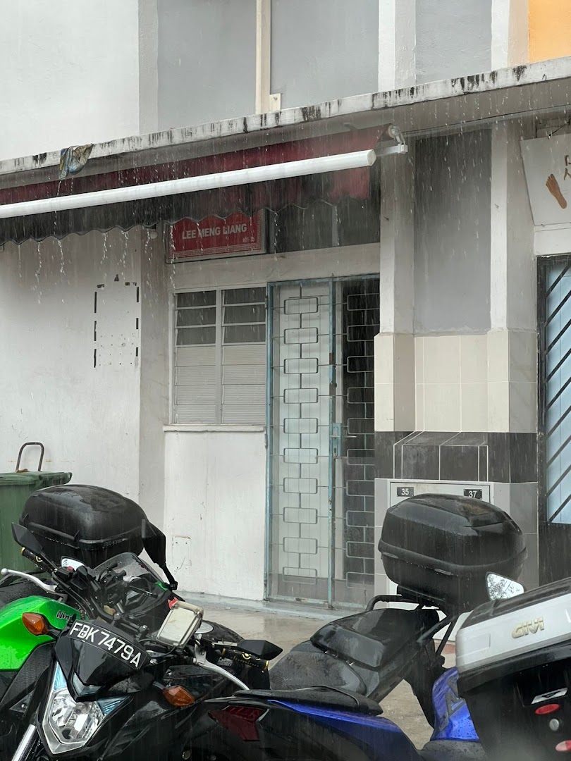 The shop front of Lee Meng Liang Therapy on a rainy day, with motorcycles parked outside.