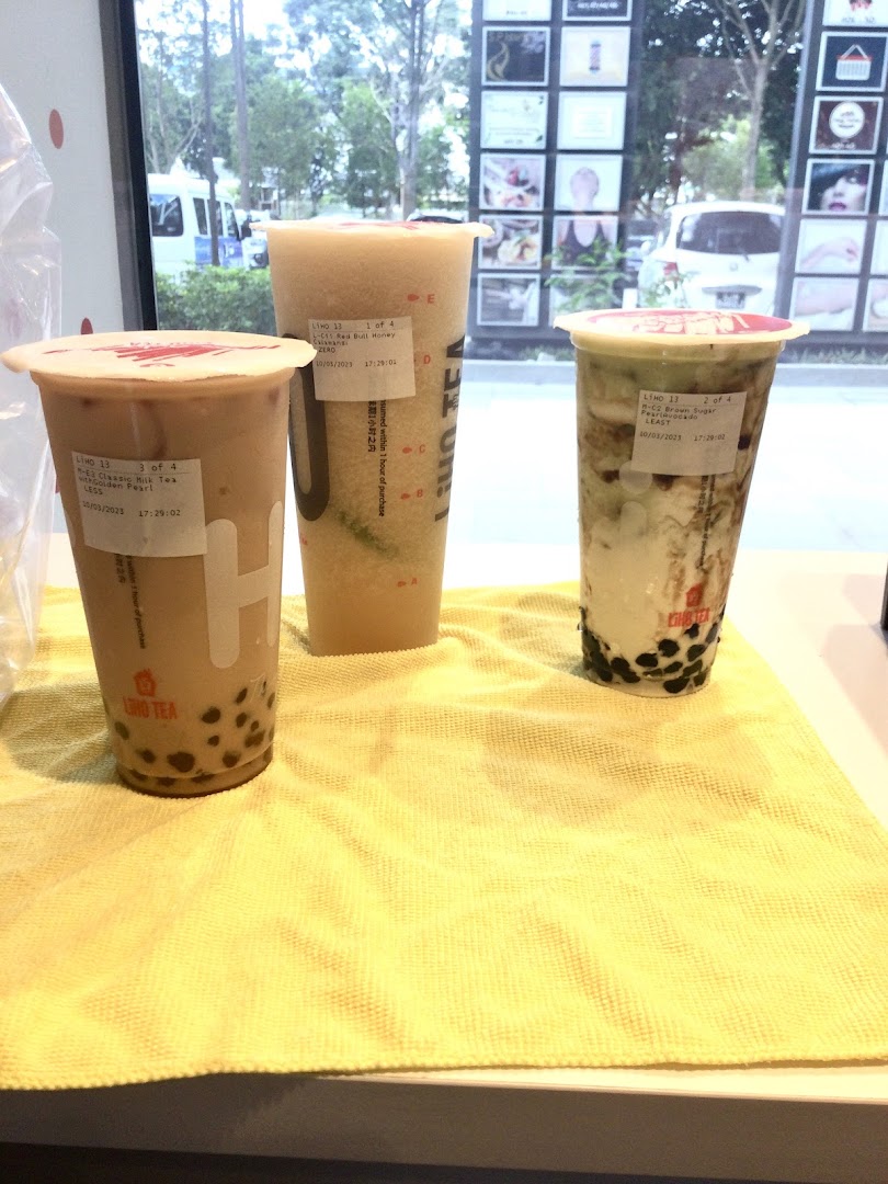 Three refreshing LiHO TEA bubble tea drinks, including milk tea and fruit blends, displayed on a counter.