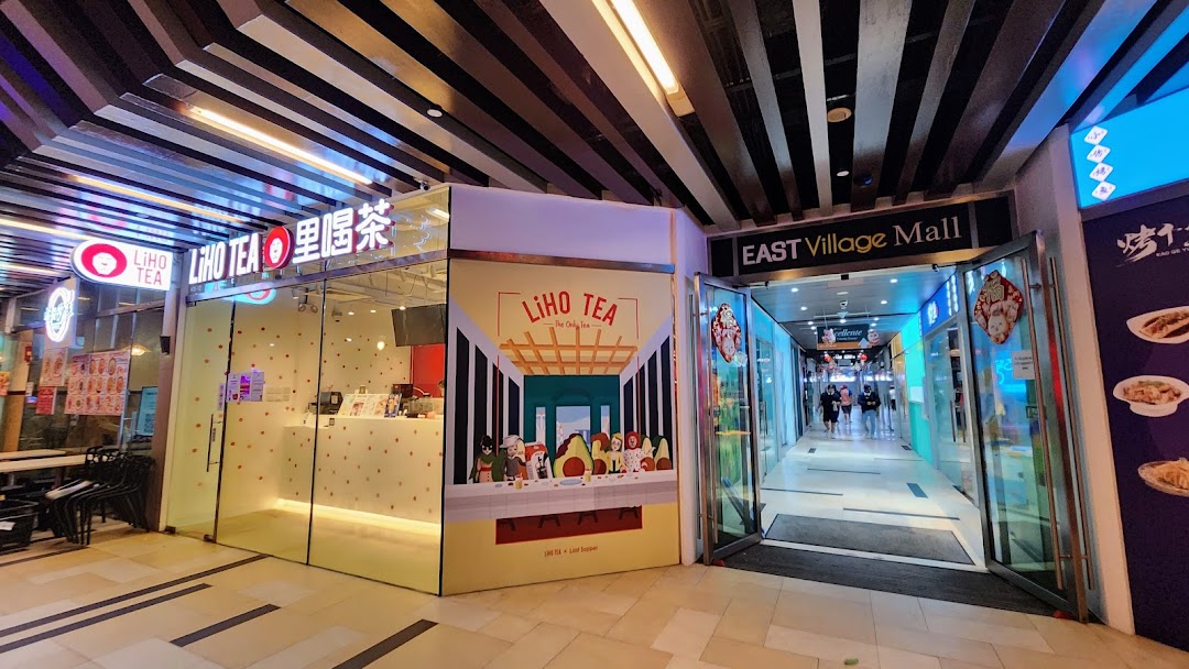 The brightly lit storefront of LiHO TEA next to the entrance of East Village Mall.