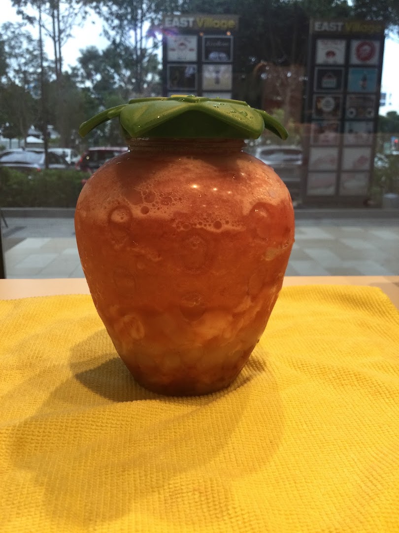 A refreshing strawberry-shaped drink from LiHO TEA on a yellow mat.