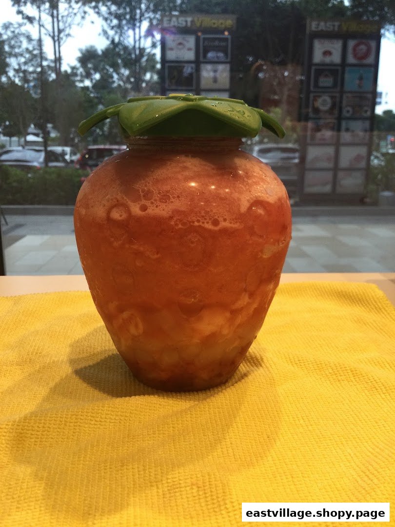 A refreshing strawberry-shaped drink from LiHO TEA on a yellow mat.