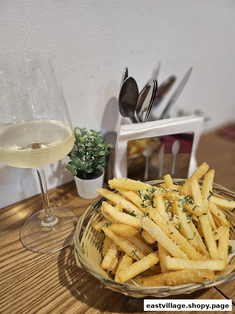 A basket of seasoned french fries and a glass of white wine on a wooden table.