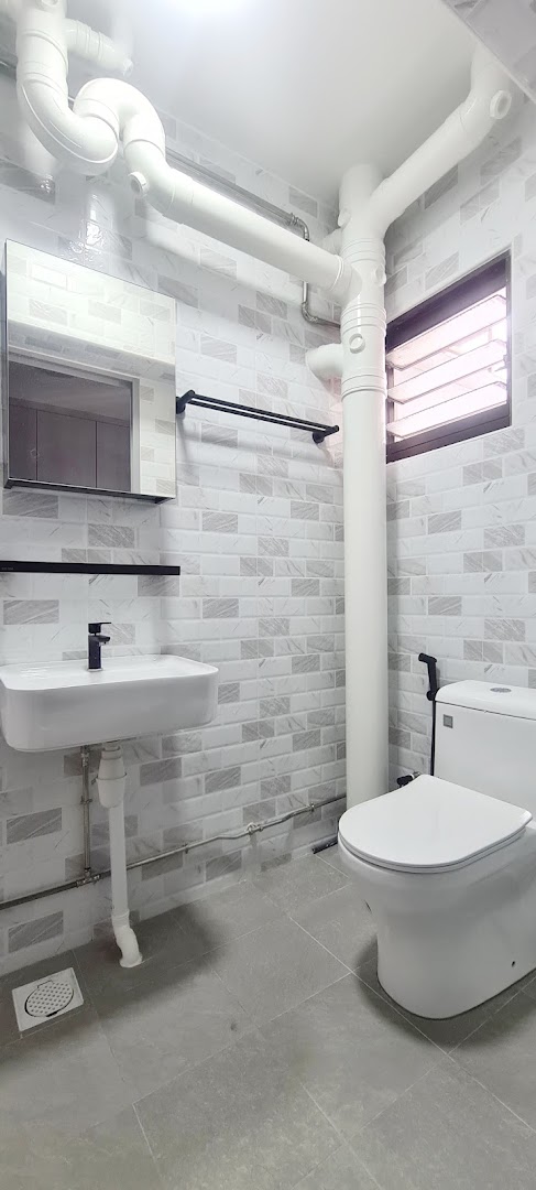 A modern bathroom featuring a white sink, toilet, and light-colored tiled walls.