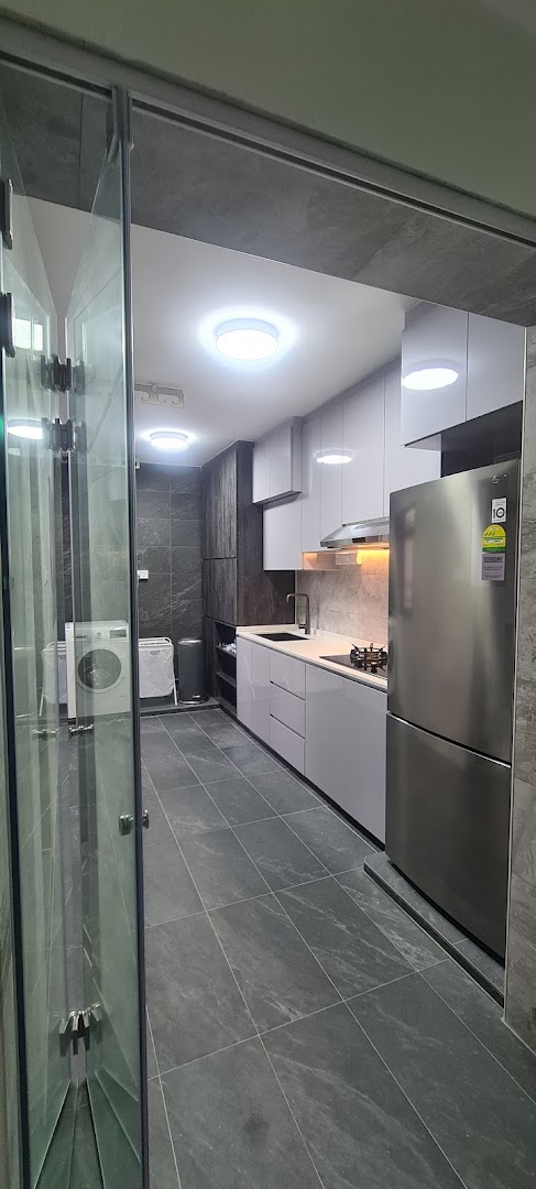 A modern kitchen and utility area featuring sleek cabinetry, dark tiled floors, and integrated appliances.