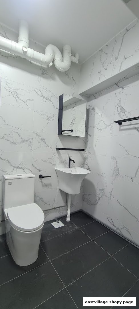 A modern bathroom featuring white marble-patterned tiles, a toilet, and a sleek sink with black fixtures.