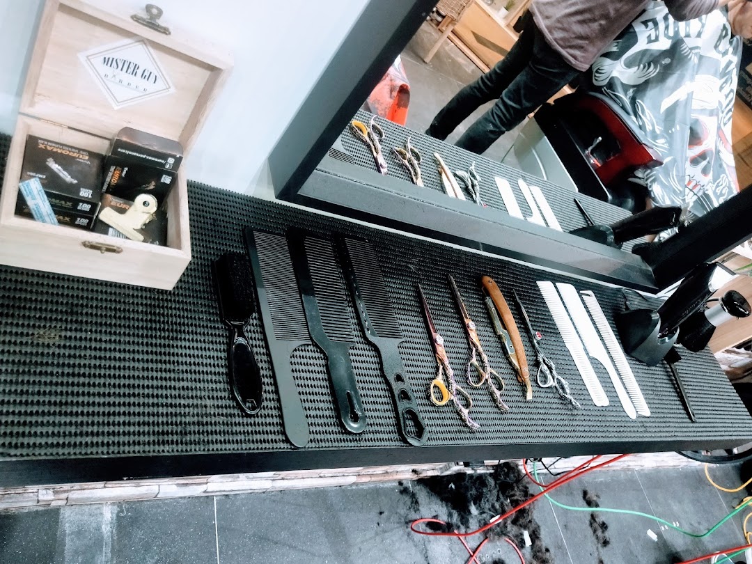 Close-up of barber tools including combs, scissors, and razors on a textured mat, ready for use.