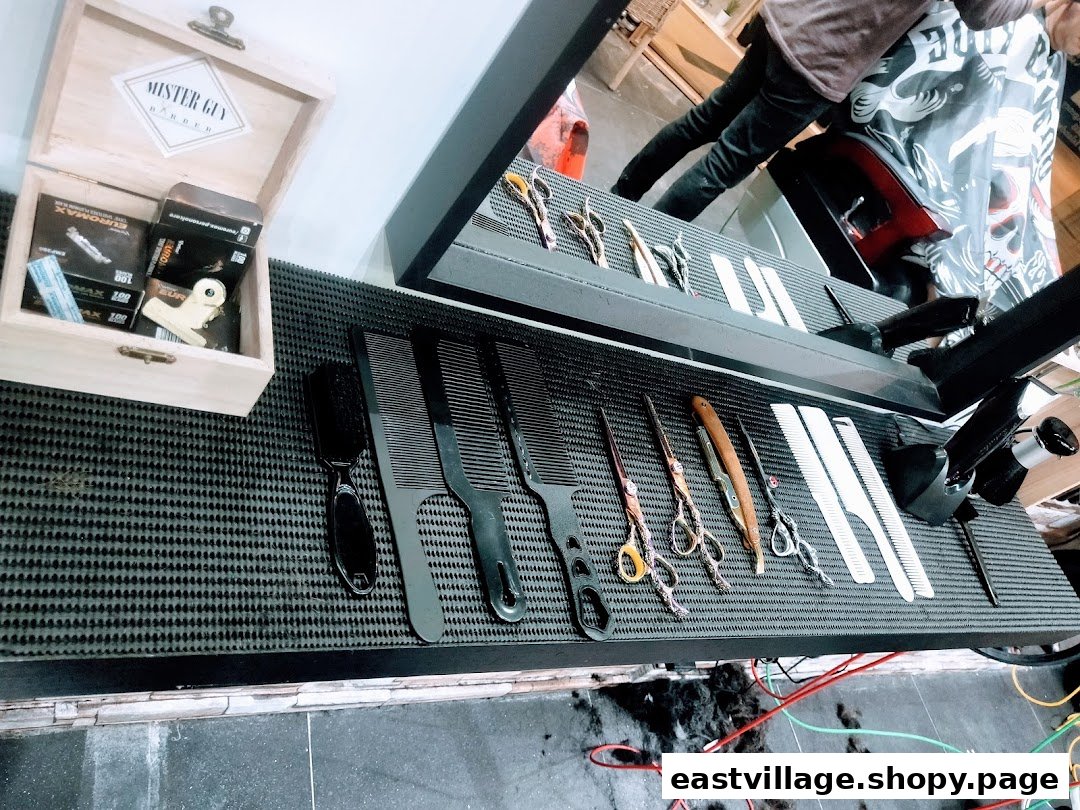 Close-up of barber tools including combs, scissors, and razors on a textured mat, ready for use.