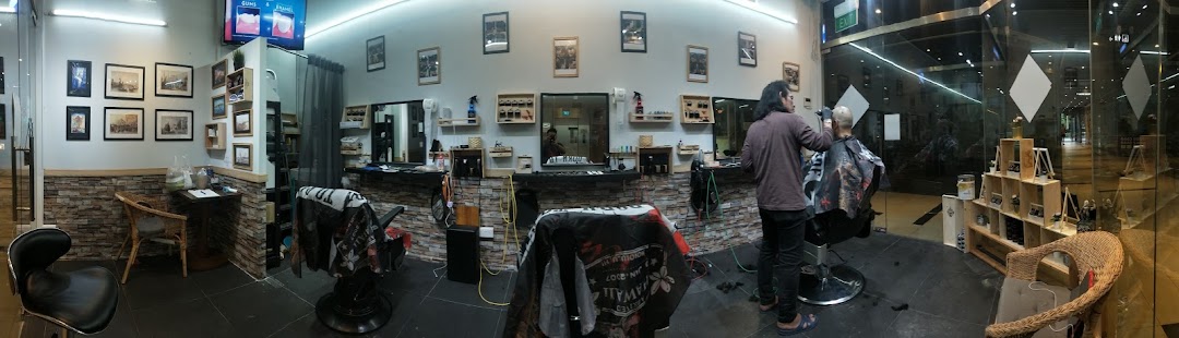 A barber cuts a client's hair inside Mister Guy Barber, showcasing the shop's modern interior and styling stations.