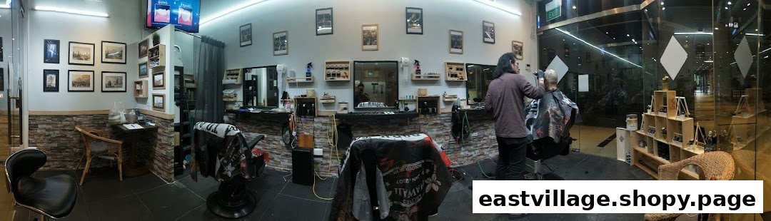 A barber cuts a client's hair inside Mister Guy Barber, showcasing the shop's modern interior and styling stations.