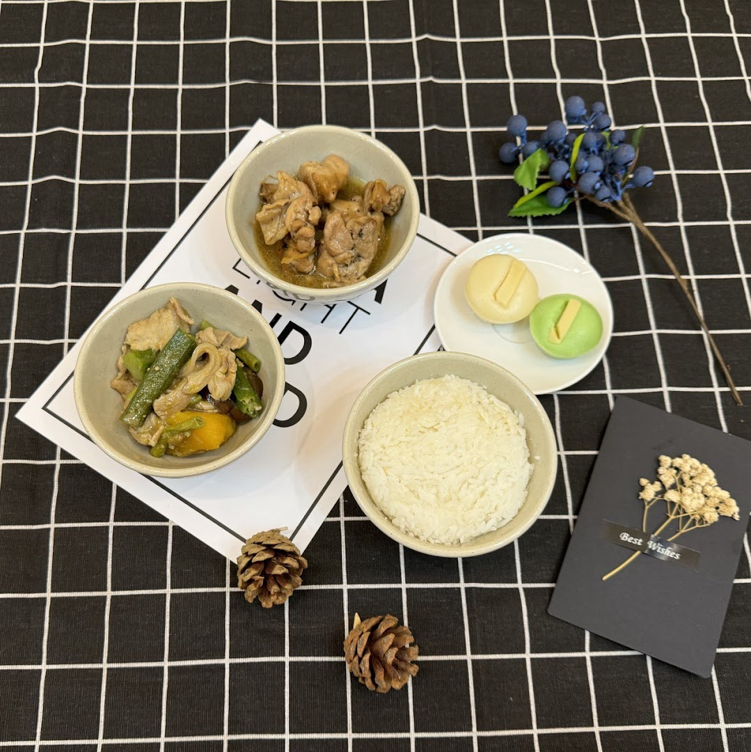 A delightful meal set featuring rice, two savory dishes, and sweet buns on a checkered cloth.